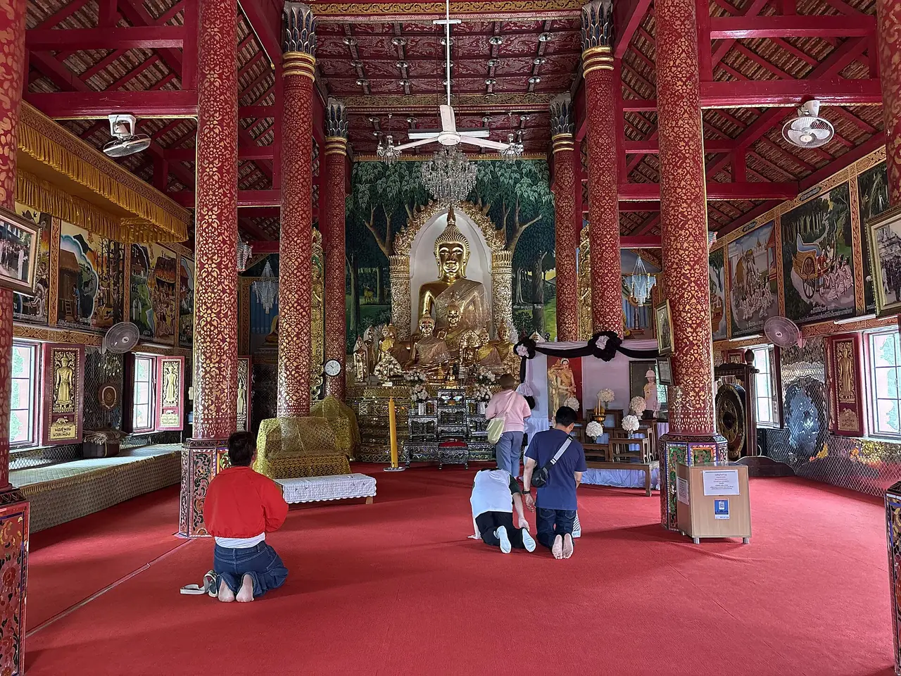 Worshippers kneeling before the Buddha image inside the viharn at Wat Phra Yuen