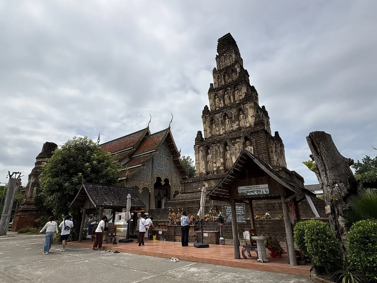 The stepped chedi of Wat Kukut, also called Wat Chamthewi, with visitors in the foreground
