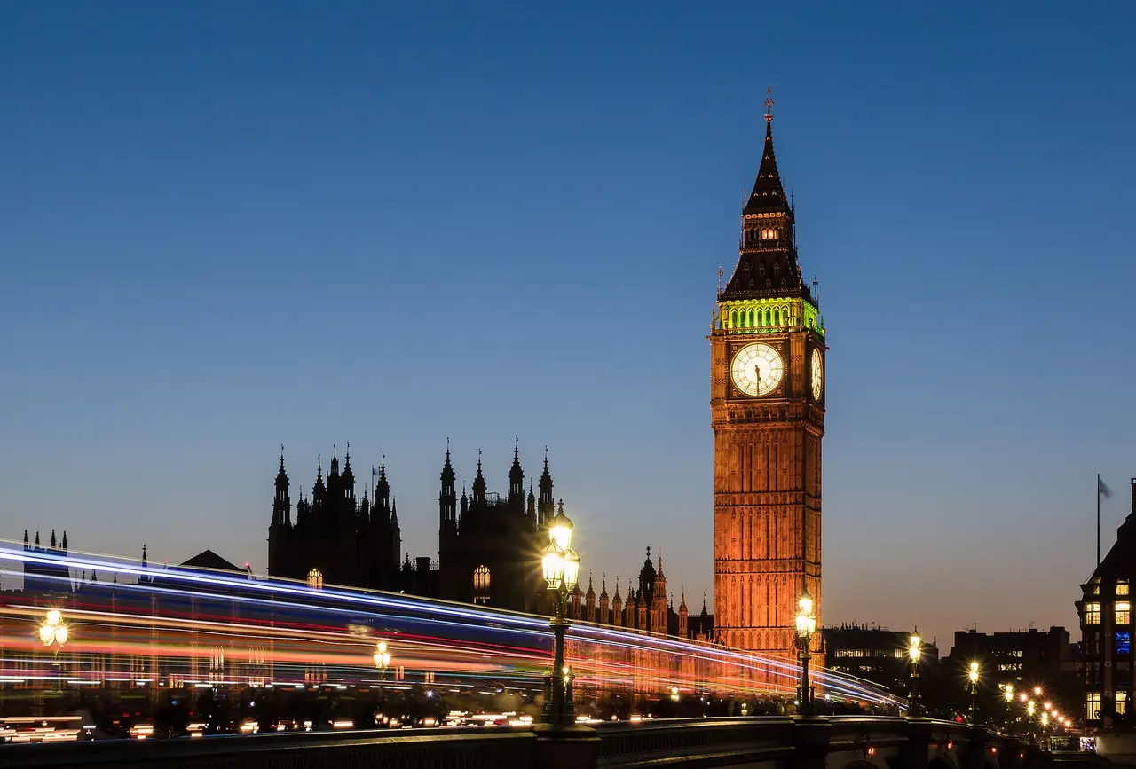 Big Ben (หอ Elizabeth Tower) ยามพลบค่ำ มีแสงไฟรถวิ่งบนสะพาน Westminster ภาพถ่ายจาก Wikimedia Commons