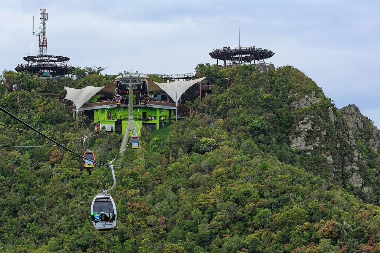 สถานียอดและกระเช้าที่แล่นอยู่เหนือป่า มองเห็นแท่นชมวิวบนยอดเขา (ภาพสถานี)