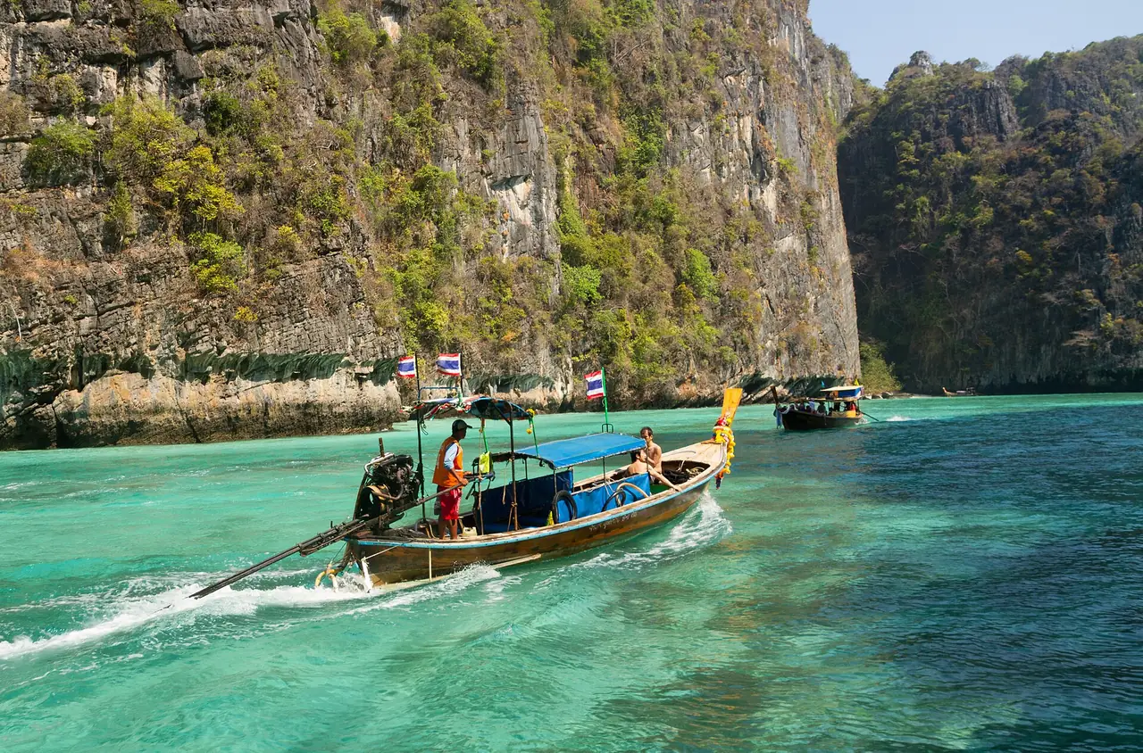 A longtail boat in the narrow waters beside the Phi Phi Leh cliffs, on the usual route between the bays.
