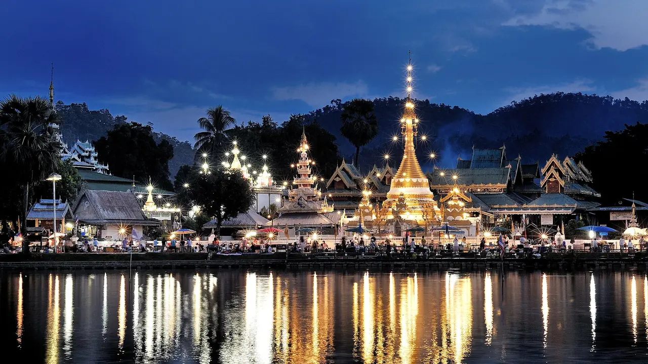 ผู้คนริมหนองจองคำยามค่ำ วัดจองกลางและวัดจองคำประดับไฟสะท้อนผิวน้ำ ภาพถ่ายจาก Wikimedia Commons