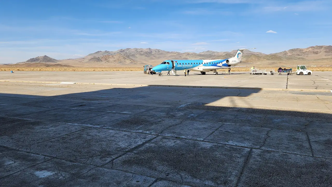 เครื่องบินเล็กของ Aero Mongolia บนลานบินกลางเทือกเขาหินที่สนามบินโควด์ ภาพชื่อไฟล์ Aero Mongolia Embraer ERJ 145 at Khovd Airport ภาพถ่ายจาก Wikimedia Commons ผู้ถ่าย BatboldDorjgurkhem สัญญา CC BY 4.0