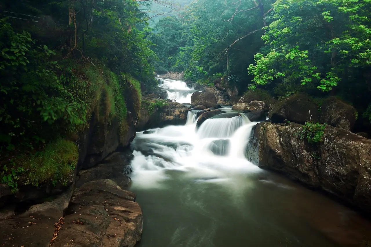 Nang Rong Waterfall: a cascade over granite boulders in forest, photographed with a long exposure