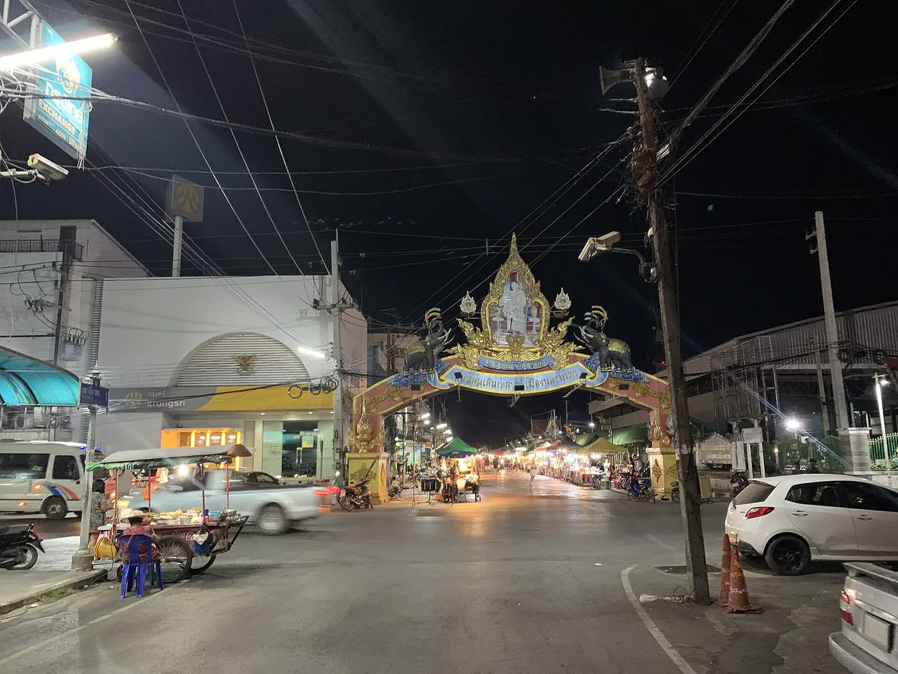 Evening market street under a decorated arch in Nakhon Nayok town