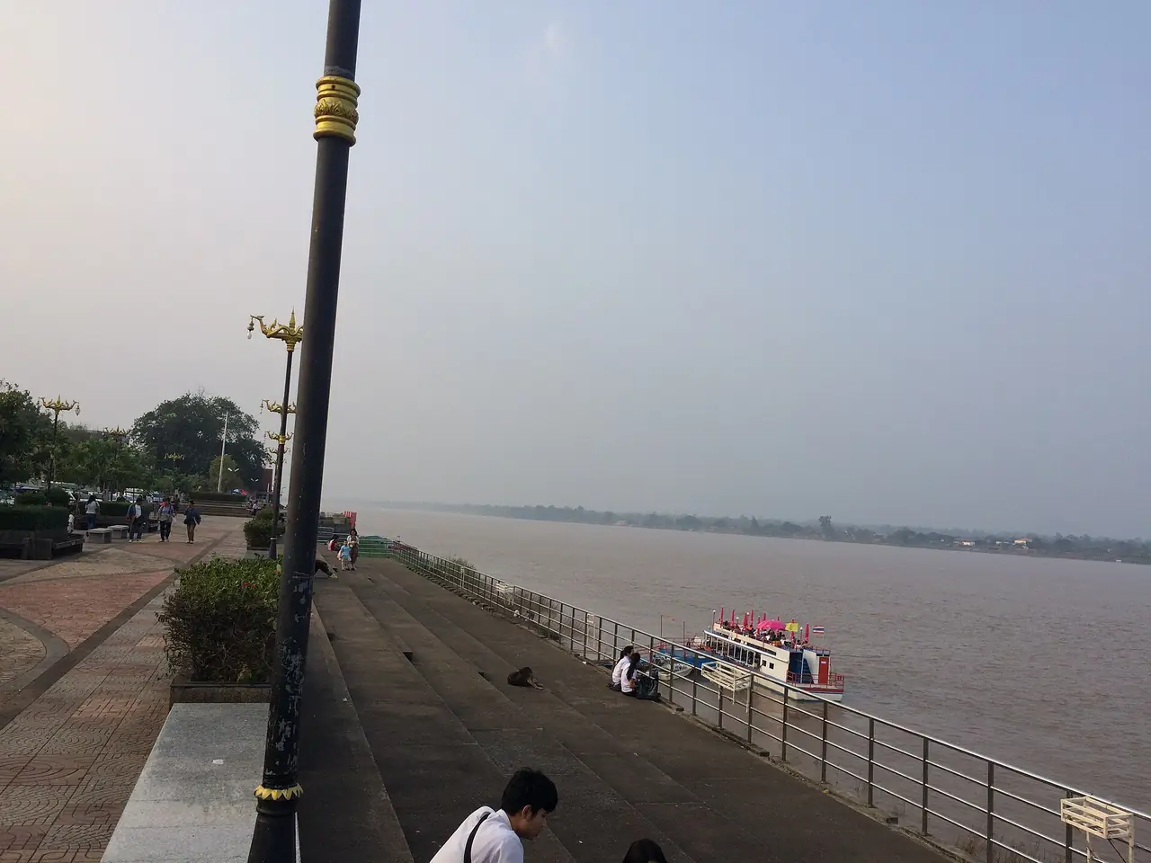 ทางเดินริมแม่น้ำโขงในตัวเมืองนครพนม มีเรือจอดอยู่ริมตลิ่ง