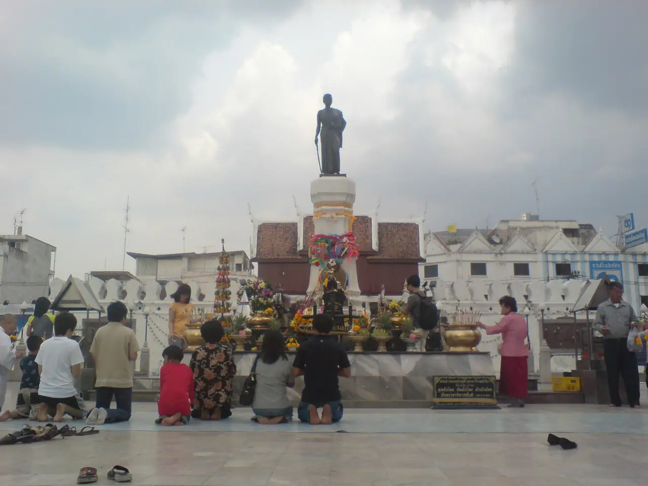 People kneeling and making offerings in front of the Ya Mo statue