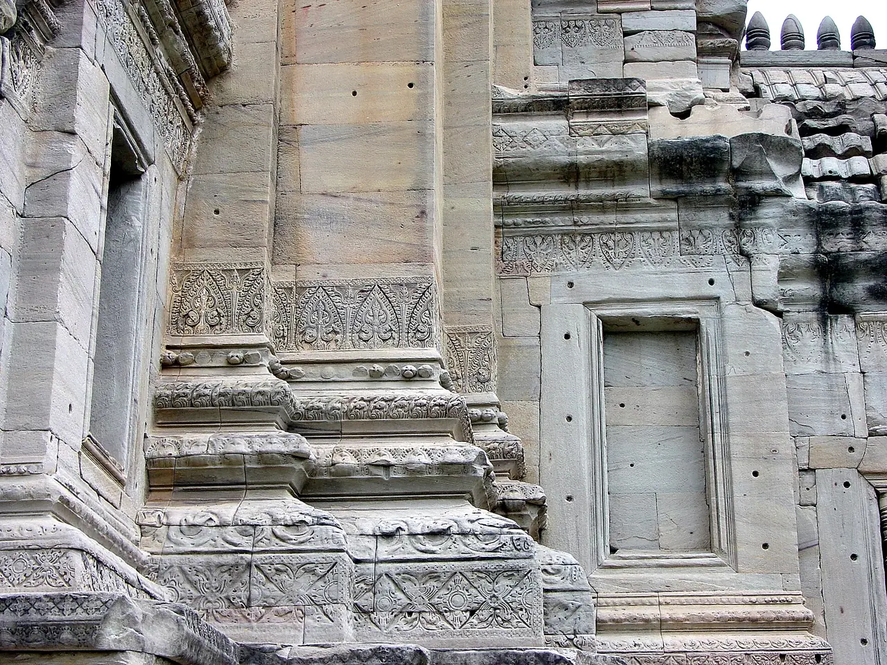 ลายสลักเส้นขอบและบัวฐานที่ผนังของปราสาทประธานพิมาย ภาพถ่ายจาก Wikimedia Commons