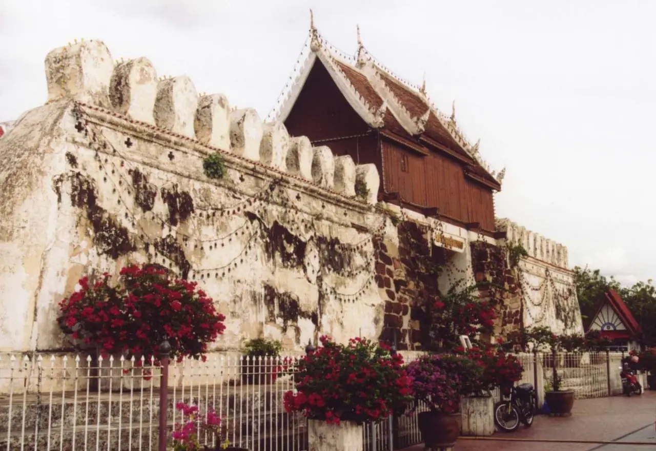 ประตูชุมพลและกำแพงเมืองตอนกลางวัน มีดอกไม้ประดับด้านหน้า ภาพถ่ายจาก Wikimedia Commons