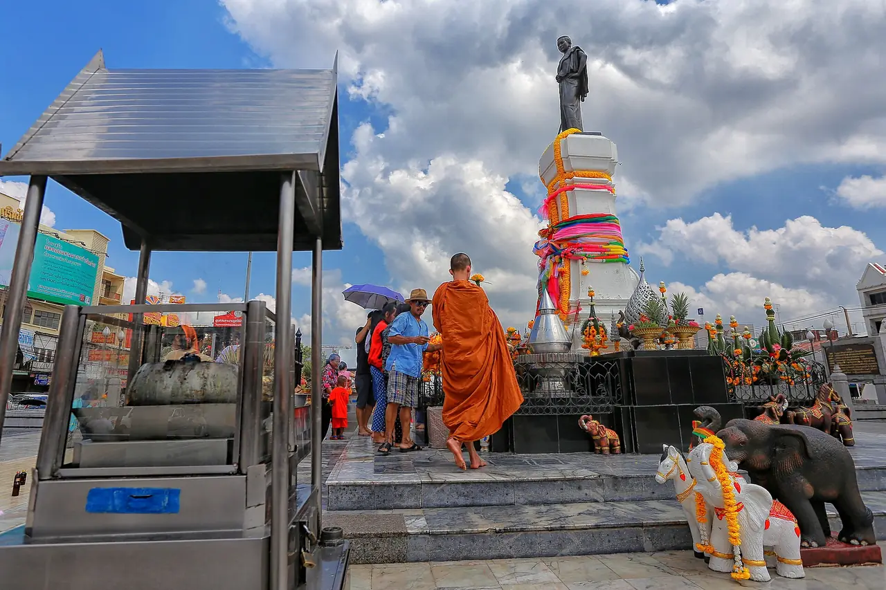 พระสงฆ์และผู้มากราบไหว้หน้าอนุสาวรีย์ท้าวสุรนารี มีรูปช้างและม้าถวายตั้งอยู่ ภาพถ่ายจาก Wikimedia Commons