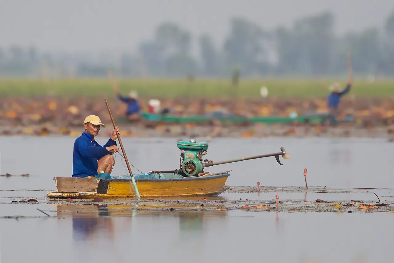 A fisherman poling a boat on Bueng Boraphet