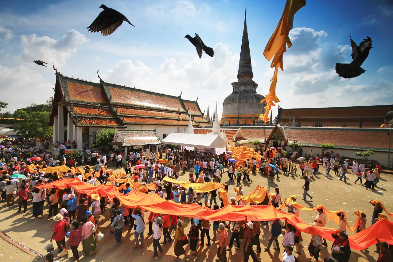 ขบวนแห่ผ้าสีส้มเข้าบริเวณวัดพระมหาธาตุ ตามชื่อไฟล์เป็นงานแห่ผ้าขึ้นธาตุ ภาพของ KOSIN SUKHUM จาก Wikimedia Commons ไม่ระบุปีที่ถ่ายในหน้าที่เราอ่าน