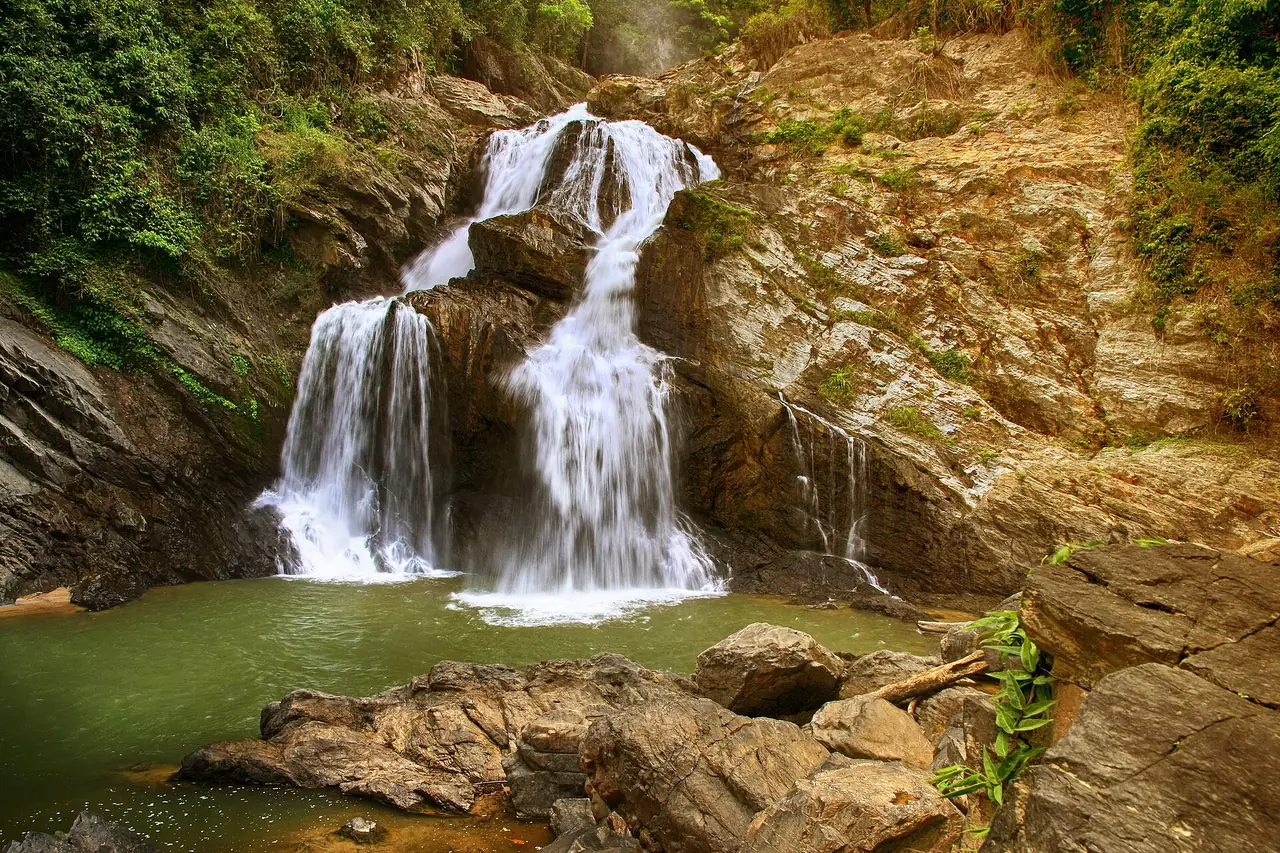 น้ำตกกรุงชิงไหลลงแอ่งน้ำสีเขียวท่ามกลางหินสีน้ำตาล ภาพของ Chaiyathat จาก Wikimedia Commons ตามคำอธิบายไฟล์เป็นอุทยานแห่งชาติเขาหลวง