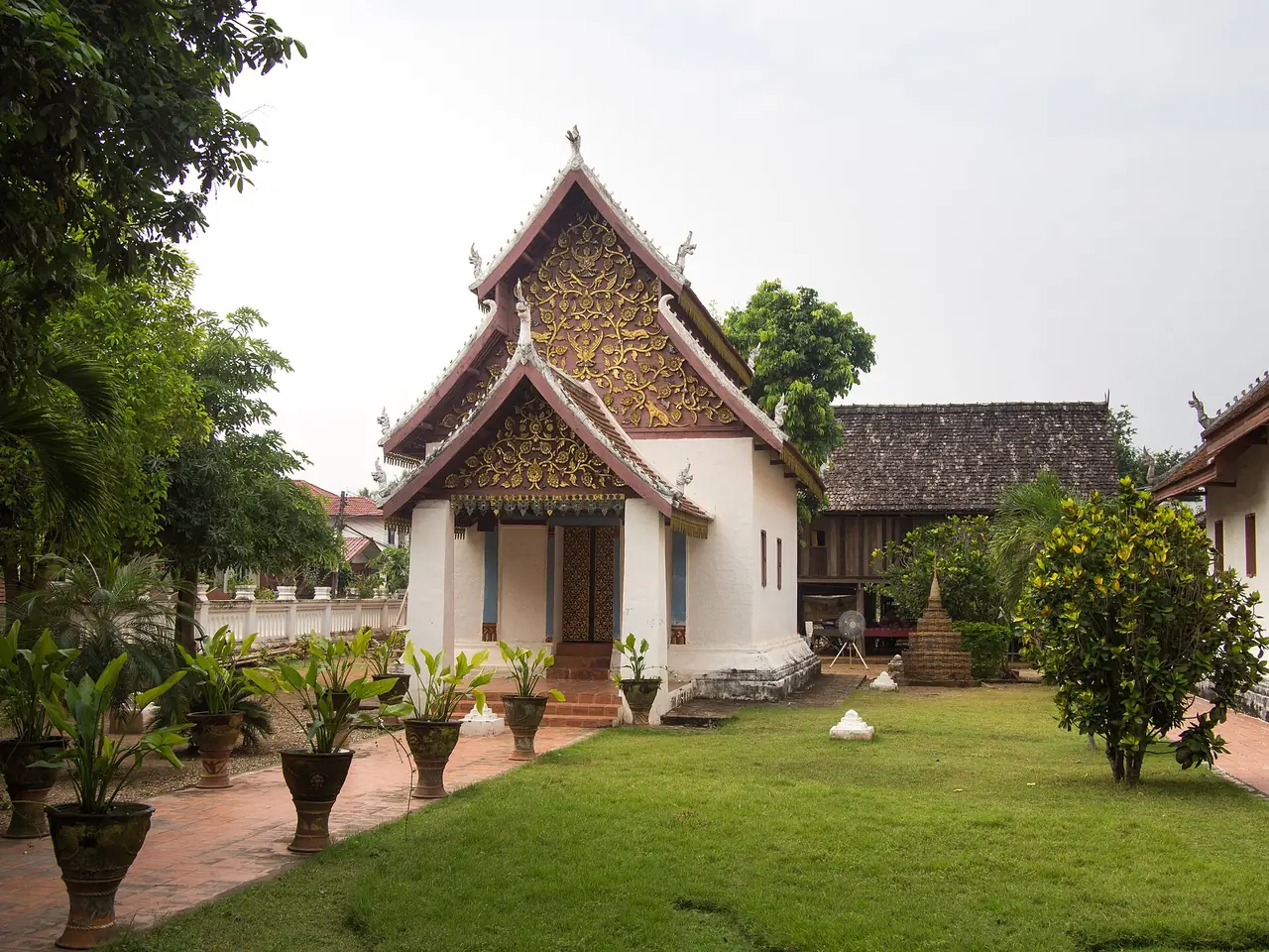 อุโบสถวัดหนองบัวในจังหวัดน่าน มีสนามหญ้าและเรือนไม้อยู่ข้าง ๆ