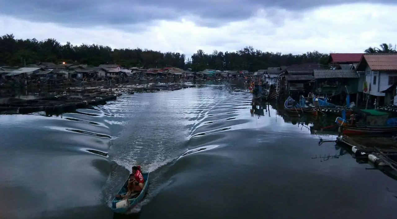ชุมชนต่อเรือกอและริมแม่น้ำบางนรา ตัวเมืองนราธิวาส มีคนพายเรือเล็กผ่านหน้า