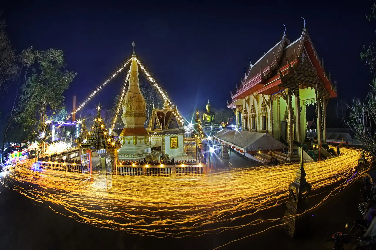ขบวนเวียนเทียนยามค่ำรอบพระธาตุที่วัดพระธาตุหาญเทาว์ แสงไฟลากเป็นเส้น