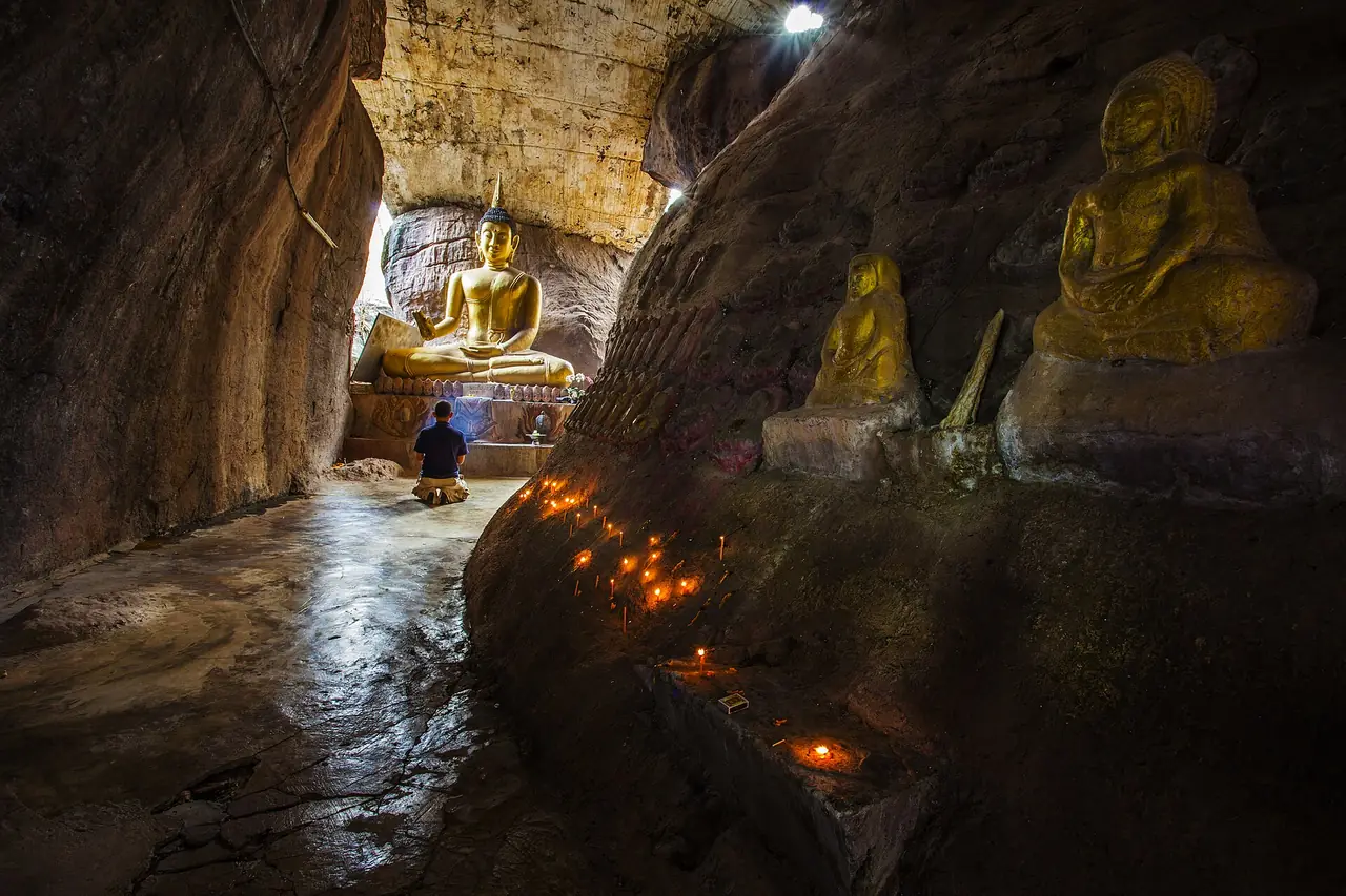 ถ้ำของวัดถ้ำกลองเพล มีพระพุทธรูปและแสงเทียนในถ้ำ