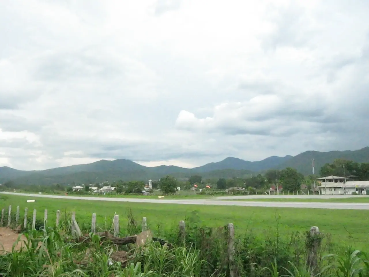 สนามบินปายในฤดูฝน มองจากริมรันเวย์ไปทางทุ่งหญ้าและเทือกเขา ภาพจาก Wikimedia Commons ผู้ถ่าย UT เป็นภาพเก่า ไม่ได้แปลว่ามีเที่ยวบินในปัจจุบัน