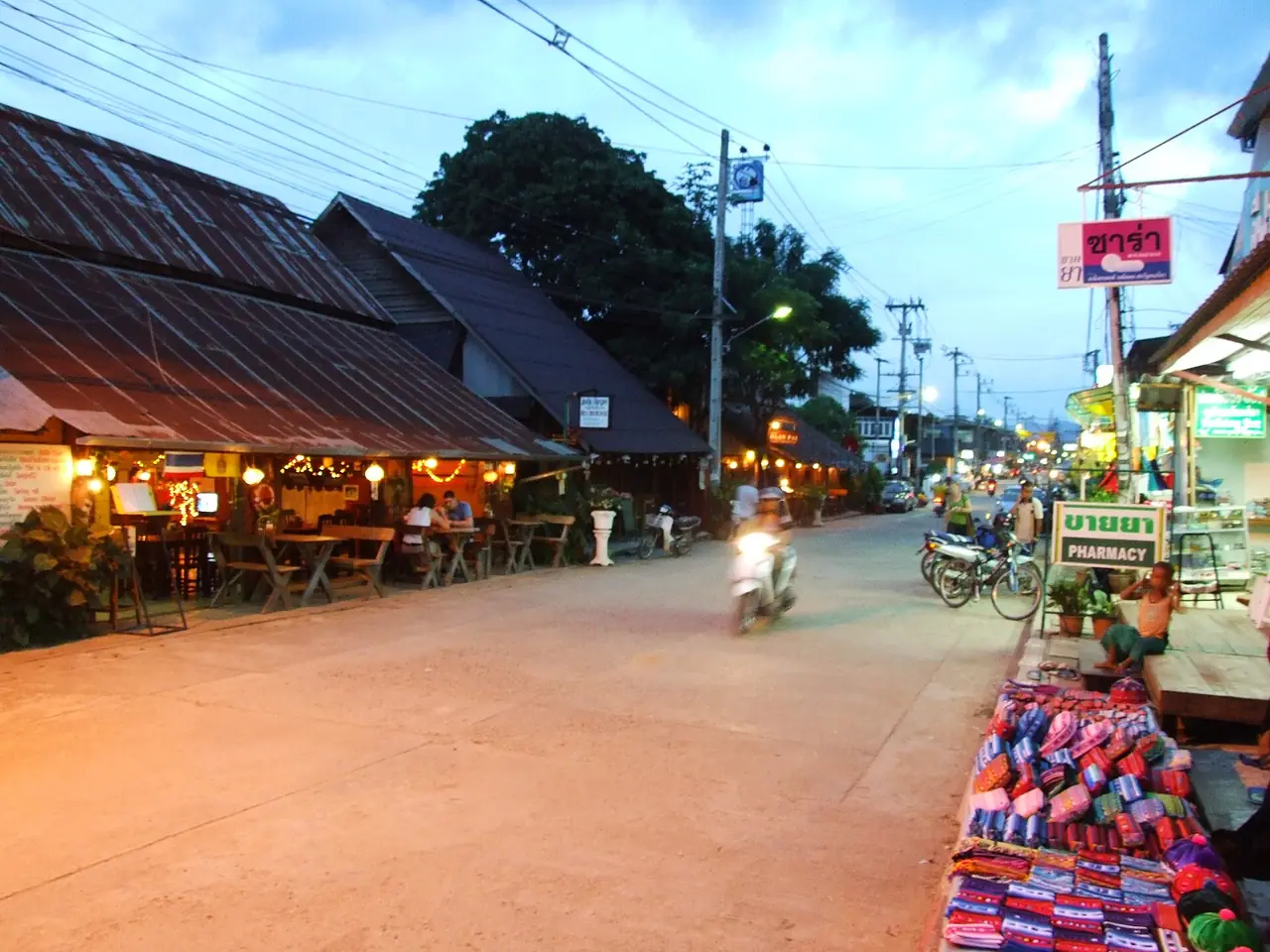 ถนนในตัวเมืองปายยามค่ำ มีร้านค้าริมทางและมอเตอร์ไซค์ ภาพจาก Wikimedia Commons ผู้ถ่าย Kansaikiwi เป็นภาพประกอบบรรยากาศตัวเมือง ไม่ระบุปีที่ถ่าย