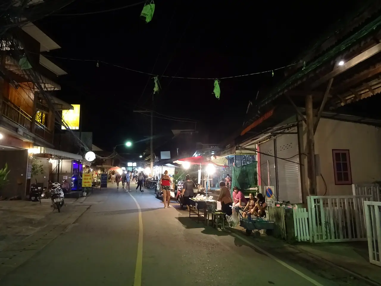 ถนนในตัวเมืองปายตอนค่ำ มีร้านค้าเปิดไฟสองข้างทาง ภาพจาก Wikimedia Commons ผู้ถ่าย Christophe95 เป็นภาพบรรยากาศ ไม่ยืนยันว่าเป็นช่วงถนนคนเดินหรือเป็นฤดูใด