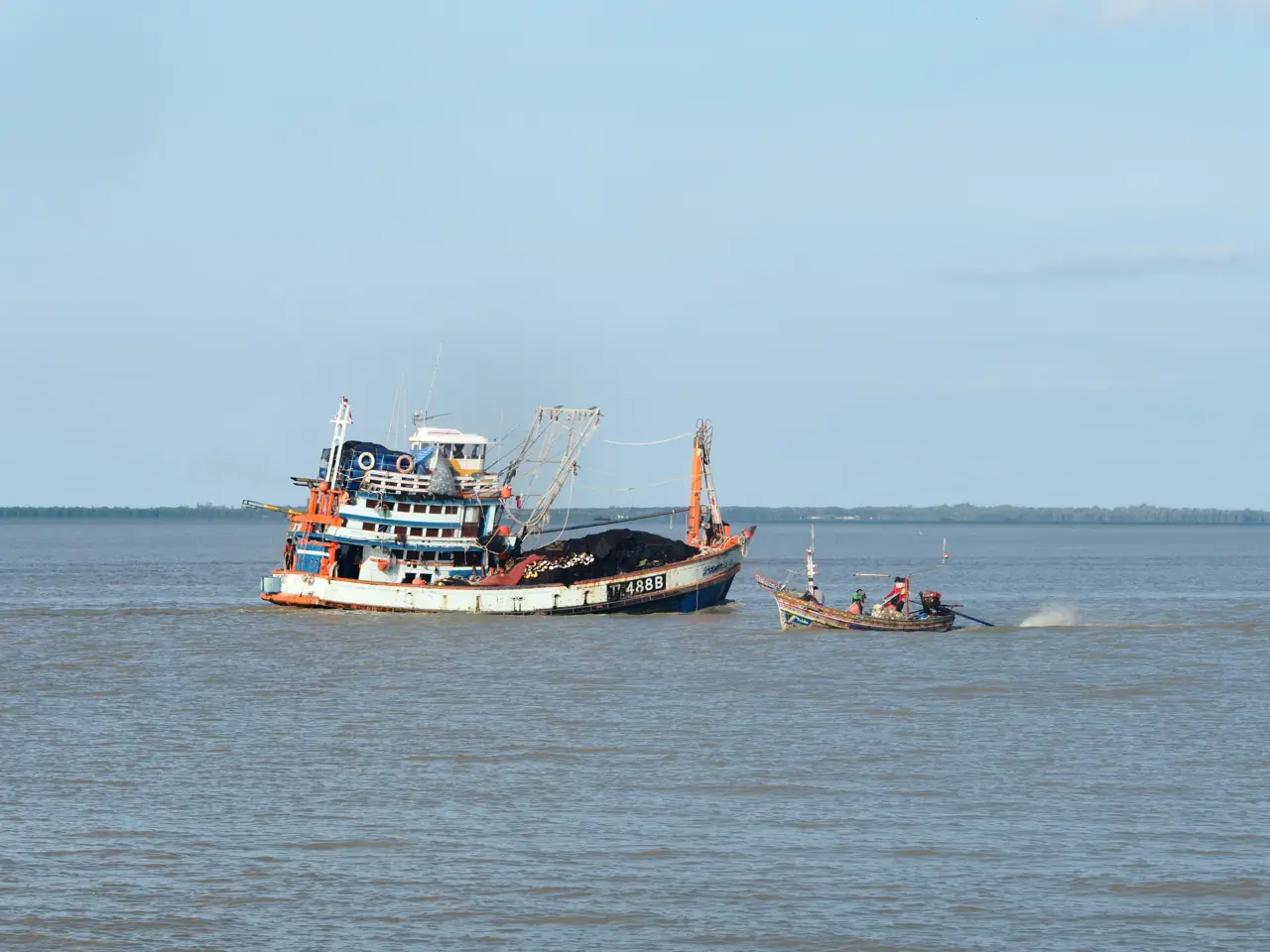 A large fishing boat and a small boat on the water off Pattani, named as the Pattani river in the Commons file
