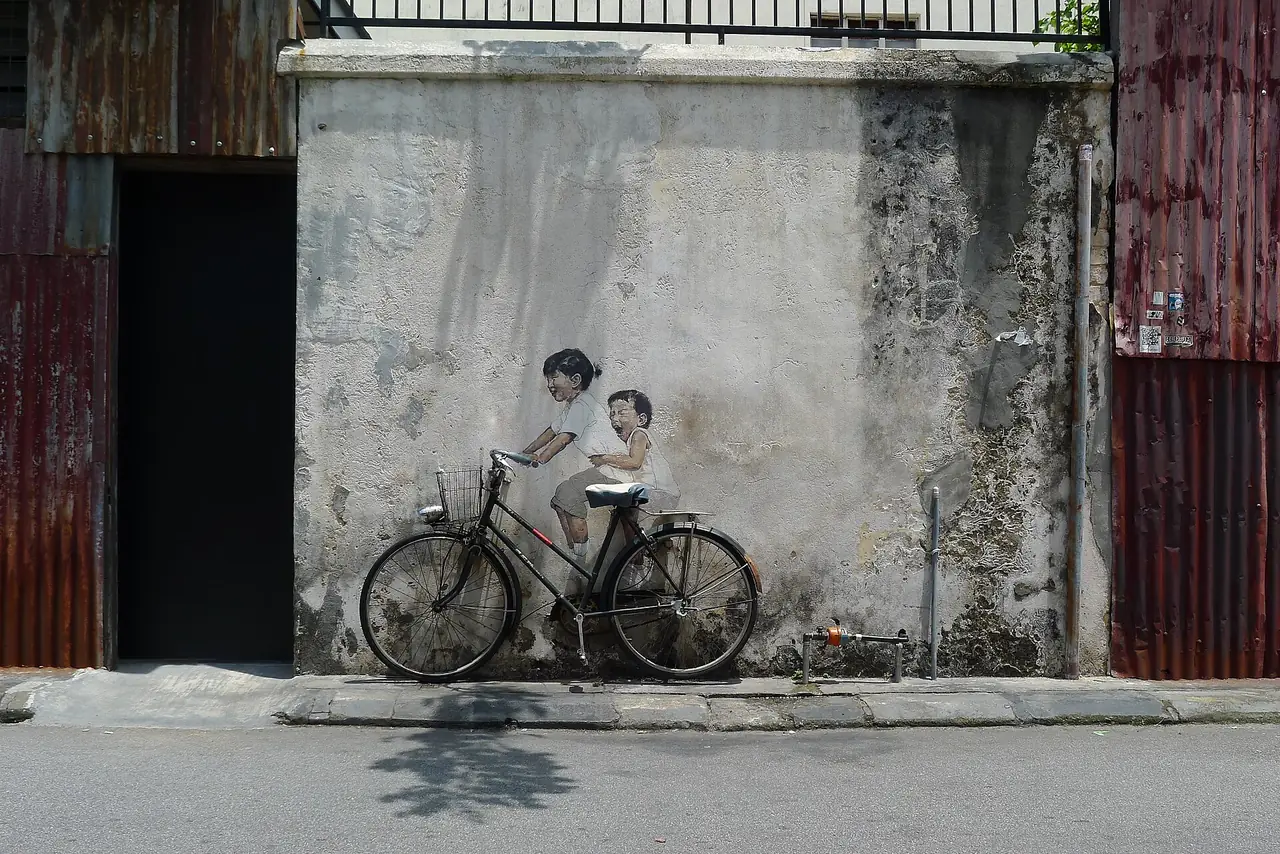 ภาพสตรีทอาร์ตเด็กขี่จักรยานบนถนน Armenian Street ผลงานของ Ernest Zacharevic ตามคำอธิบายบน Commons