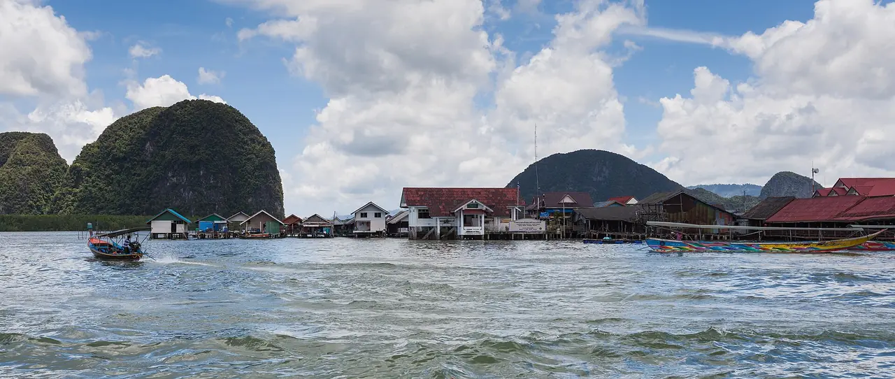 หมู่บ้านชาวประมงบ้านเกาะปันหยีที่สร้างบนเสา มีเรือหางยาวและเขาหินปูนด้านหลัง