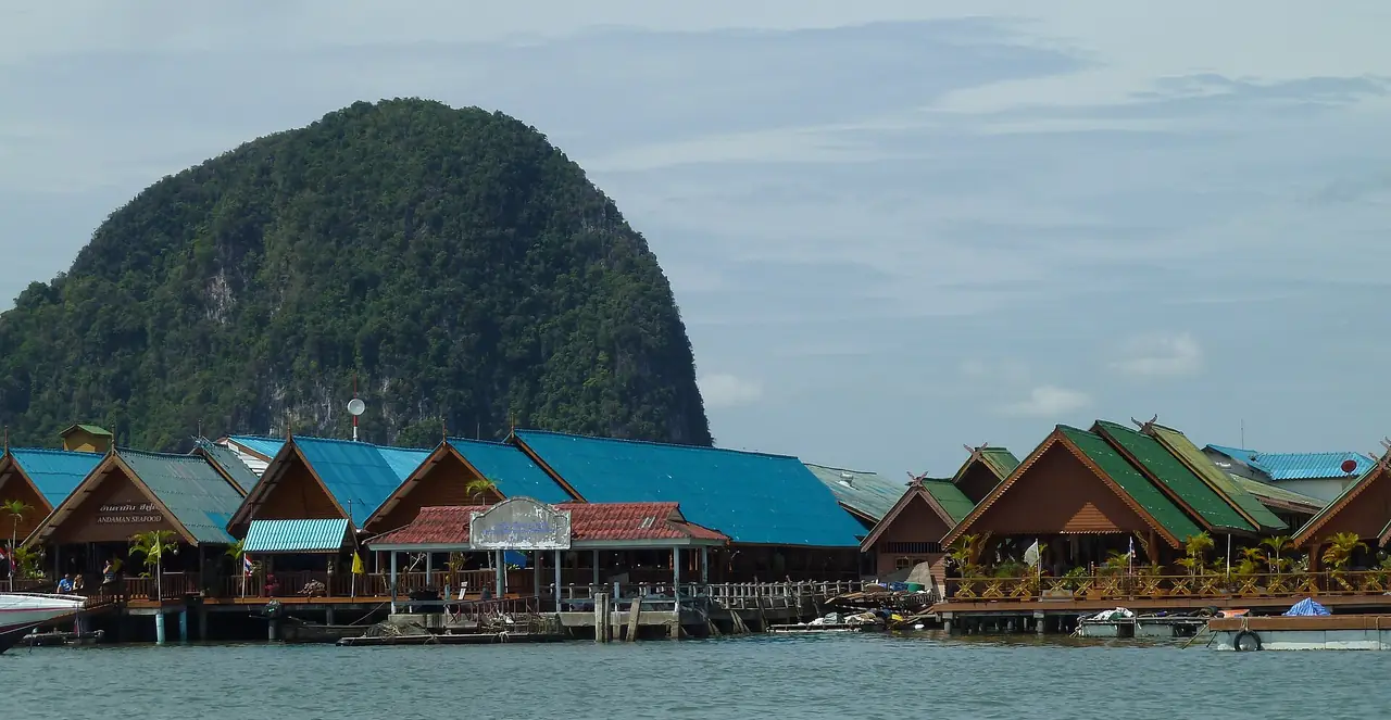 บ้านและร้านบนเสาของเกาะปันหยี มีเขาหินปูนด้านหลัง ภาพของ Deror Avi จาก Wikimedia Commons