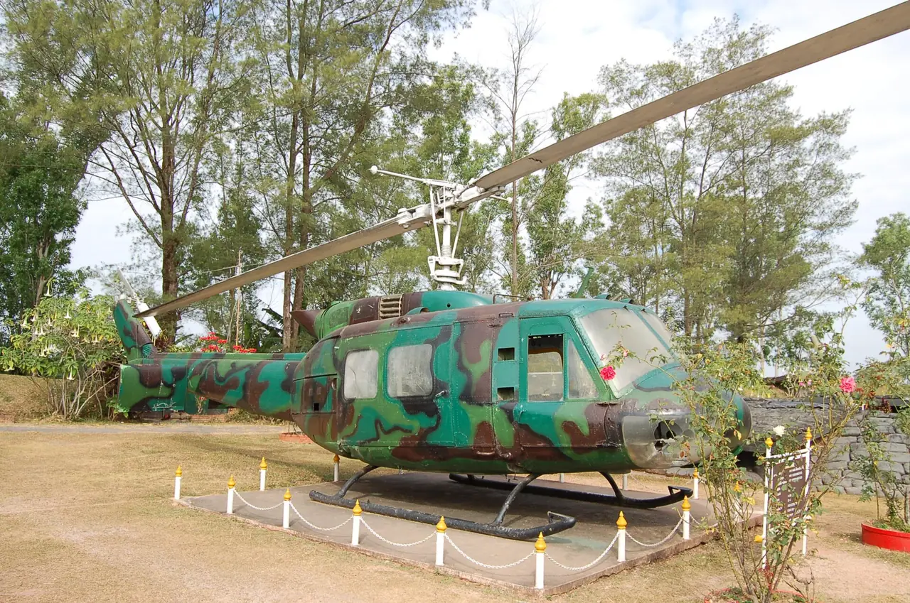A camouflaged Bell UH-1 helicopter on display at the Khao Kho War Memorial Park