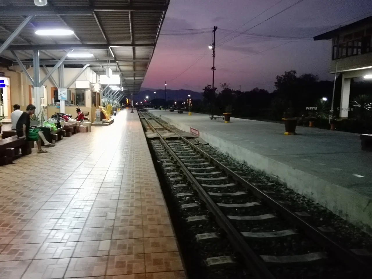 ชานชาลาสถานีรถไฟบ้านปินยามค่ำก่อนรถด่วนขบวน 52 เข้าจอด ภาพของ Paweeraphat Thasee จาก Wikimedia Commons ใบอนุญาต CC BY-SA 4.0