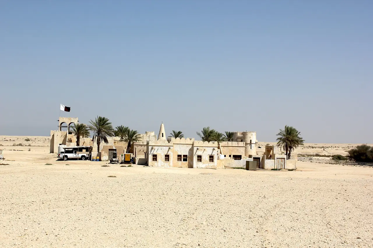 ภาพมุมไกลของ Film City ที่ Zekreet มีธงและต้นปาล์มกลางทะเลทราย ภาพจาก Wikimedia Commons ผู้ถ่าย Isabell Schulz สัญญา CC BY-SA 2.0