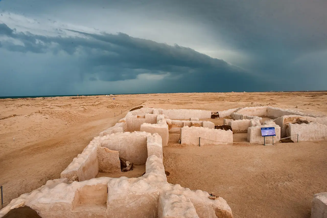 ซากกำแพงและห้องดินของเมือง Zubarah ใต้เมฆครึ้ม ภาพจาก Wikimedia Commons ผู้ถ่าย Alex Sergeev สัญญา CC BY-SA 3.0