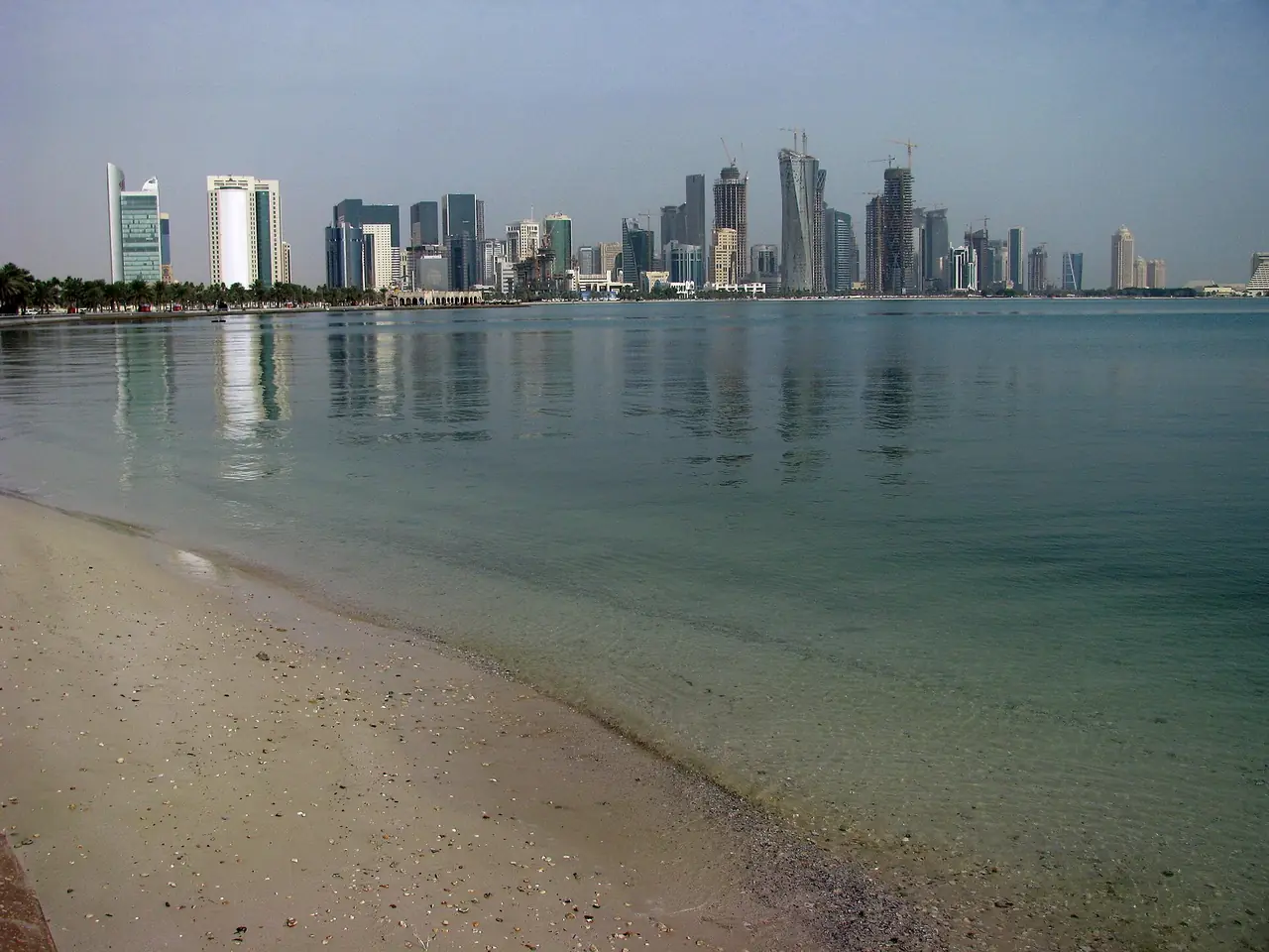 ชายหาดริมคอร์นิชโดฮากับตึกเวสต์เบย์ไกล ๆ ภาพจาก Wikimedia Commons ผู้ถ่าย Peter Dowley สัญญา CC BY 2.0 ถ่ายก่อนวันชาติกาตาร์ในปีที่ไม่ระบุ