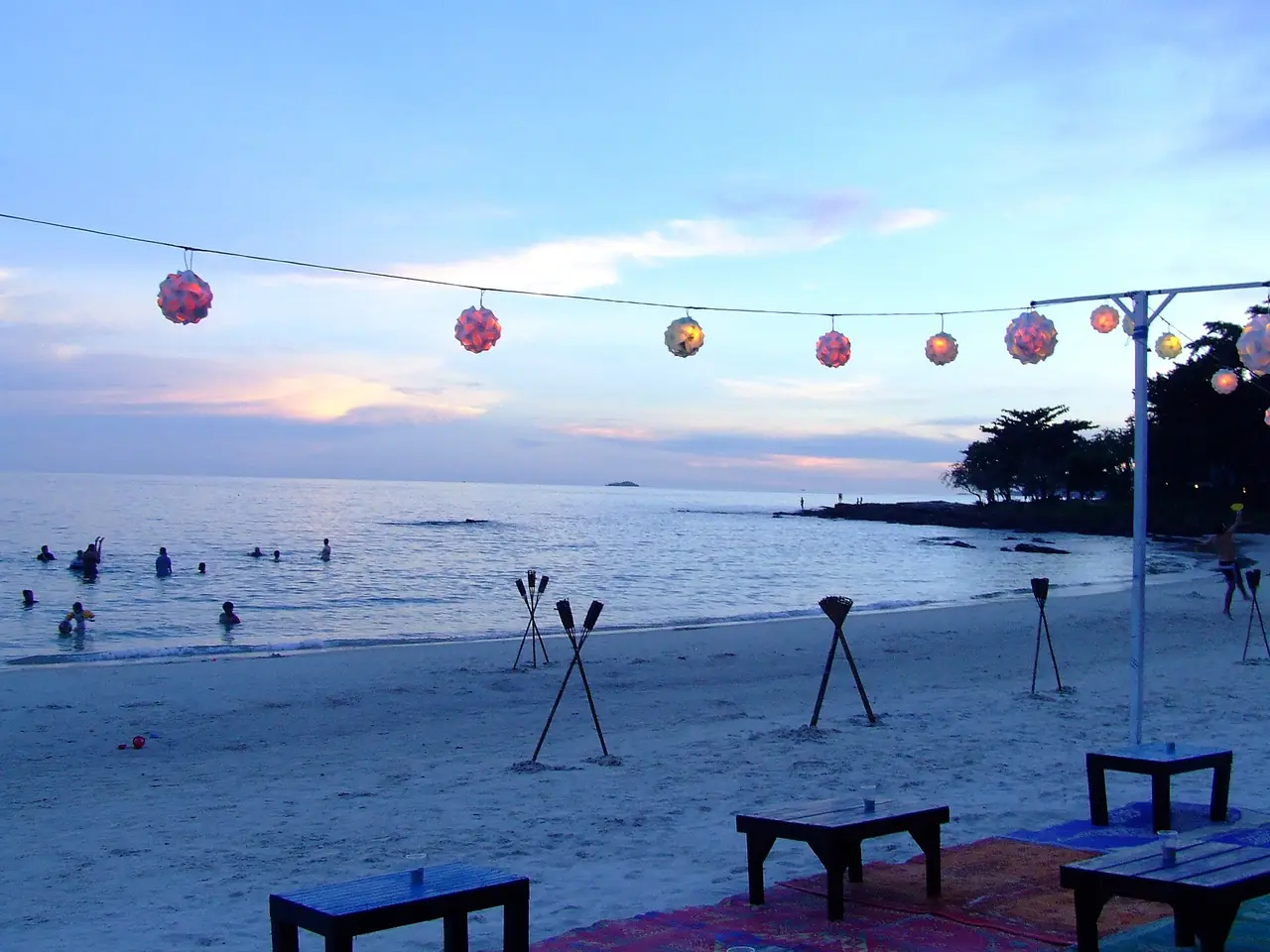 หาดในตำบลเพ มีเก้าอี้ริมหาดและโคมไฟตอนเย็น ภาพถ่ายจาก Wikimedia Commons