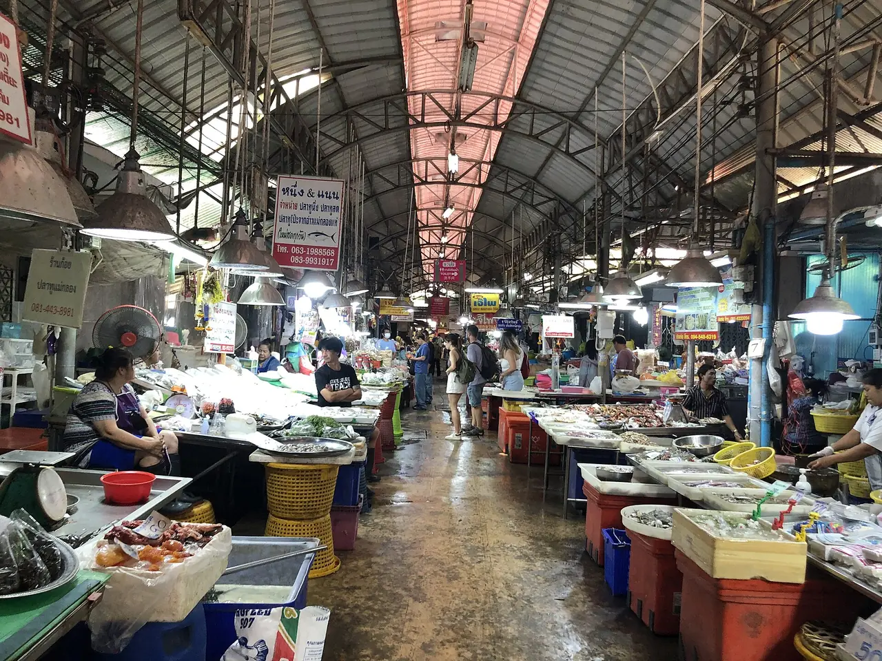 Stalls inside the Maeklong market, with seafood and produce on both sides of the aisle
