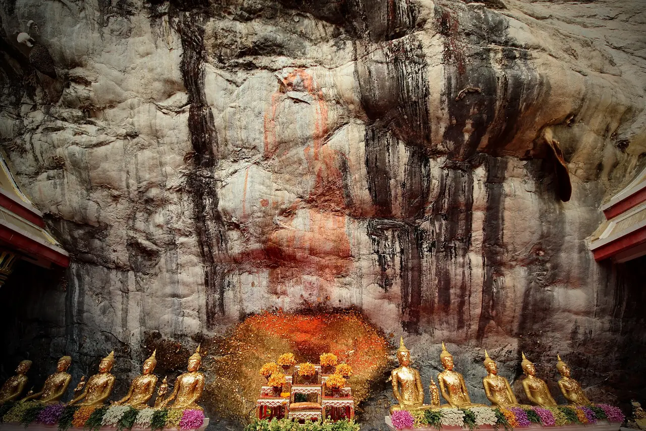 ผนังหินที่เชื่อว่ามีรอยพระพุทธฉาย พร้อมพระพุทธรูปเล็กเรียงด้านหน้า วัดพระพุทธฉาย