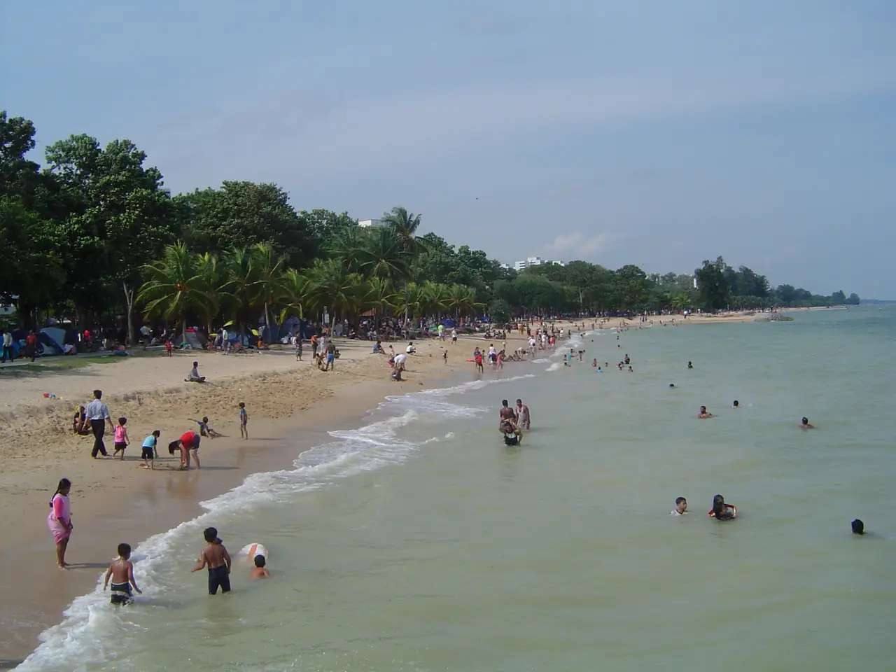 ชายหาด East Coast Park ภาพเก่าปี 2548 เห็นผู้คนเล่นน้ำและร่มไม้ริมหาด ภาพจาก Wikimedia Commons ผู้ถ่าย BertholdD. สัญญา CC BY-SA 3.0