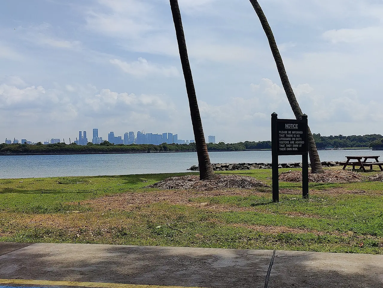 เส้นขอบฟ้าของสิงคโปร์มองจาก St John's Island เห็นป้ายประกาศว่าไม่มีไลฟ์การ์ด ภาพจาก Wikimedia Commons ผู้ถ่าย Denis Barthel สัญญา CC BY-SA 4.0 ถ่ายปี 2566