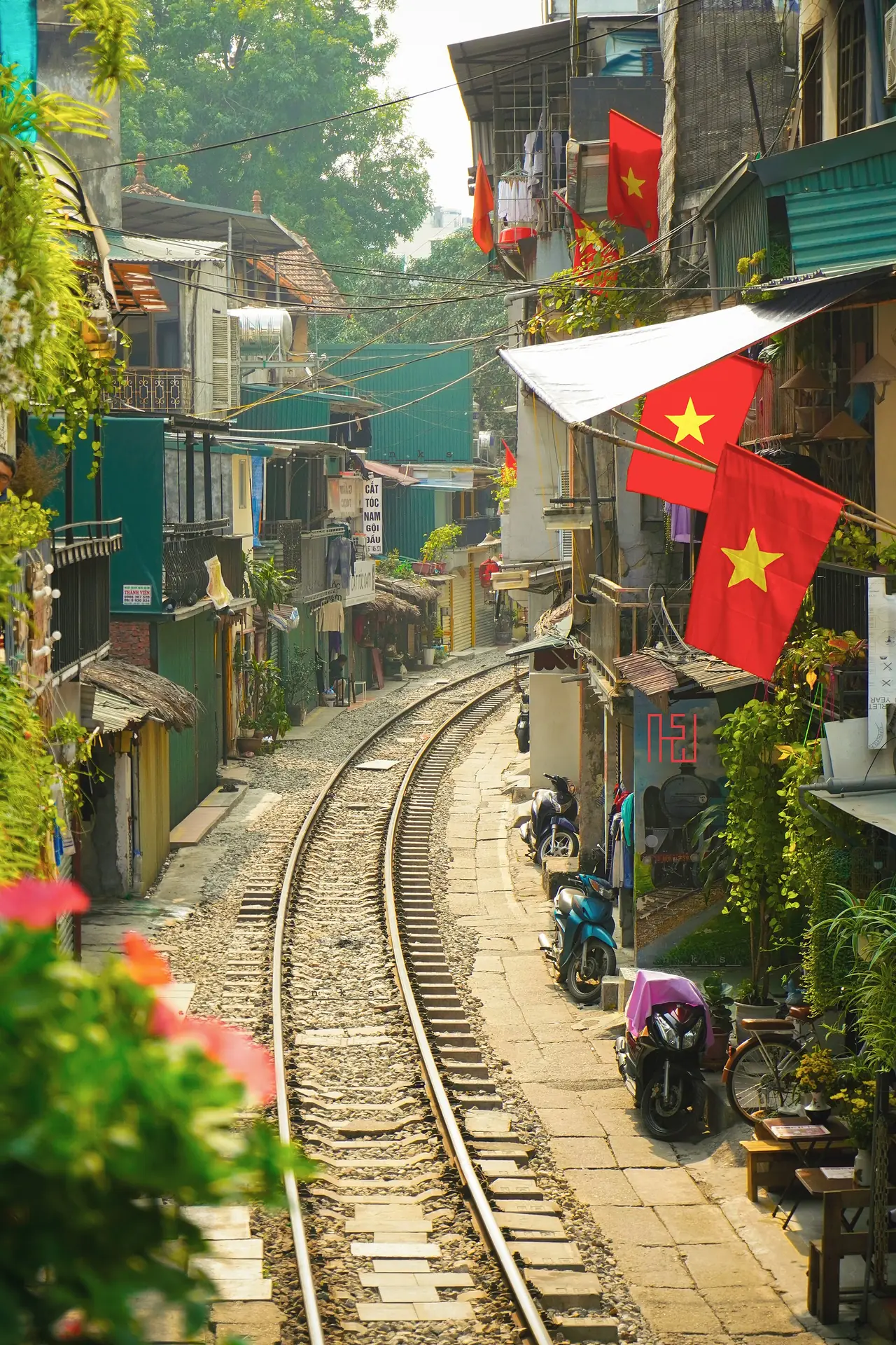 ตรอกรางรถไฟที่มีธงชาติเวียดนามและต้นไม้สองข้าง