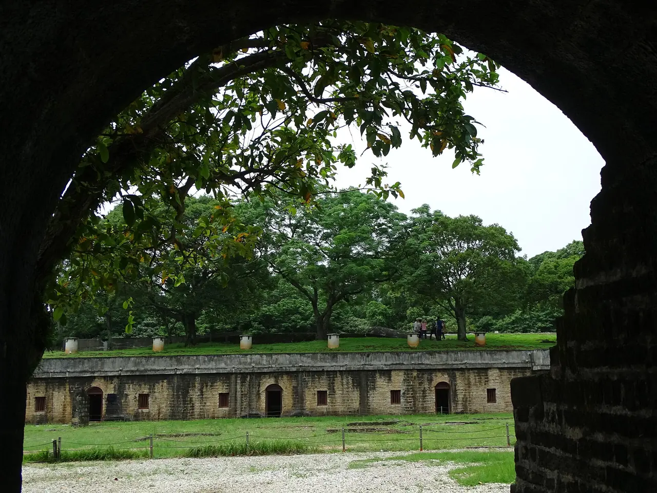 ป้อมหูเหว่ยมองลอดซุ้มประตูอิฐ เห็นแนวกำแพงป้อมและสนามหญ้า ภาพจาก Wikimedia Commons ผู้ถ่าย Adam Jones สัญญา CC BY-SA 2.0