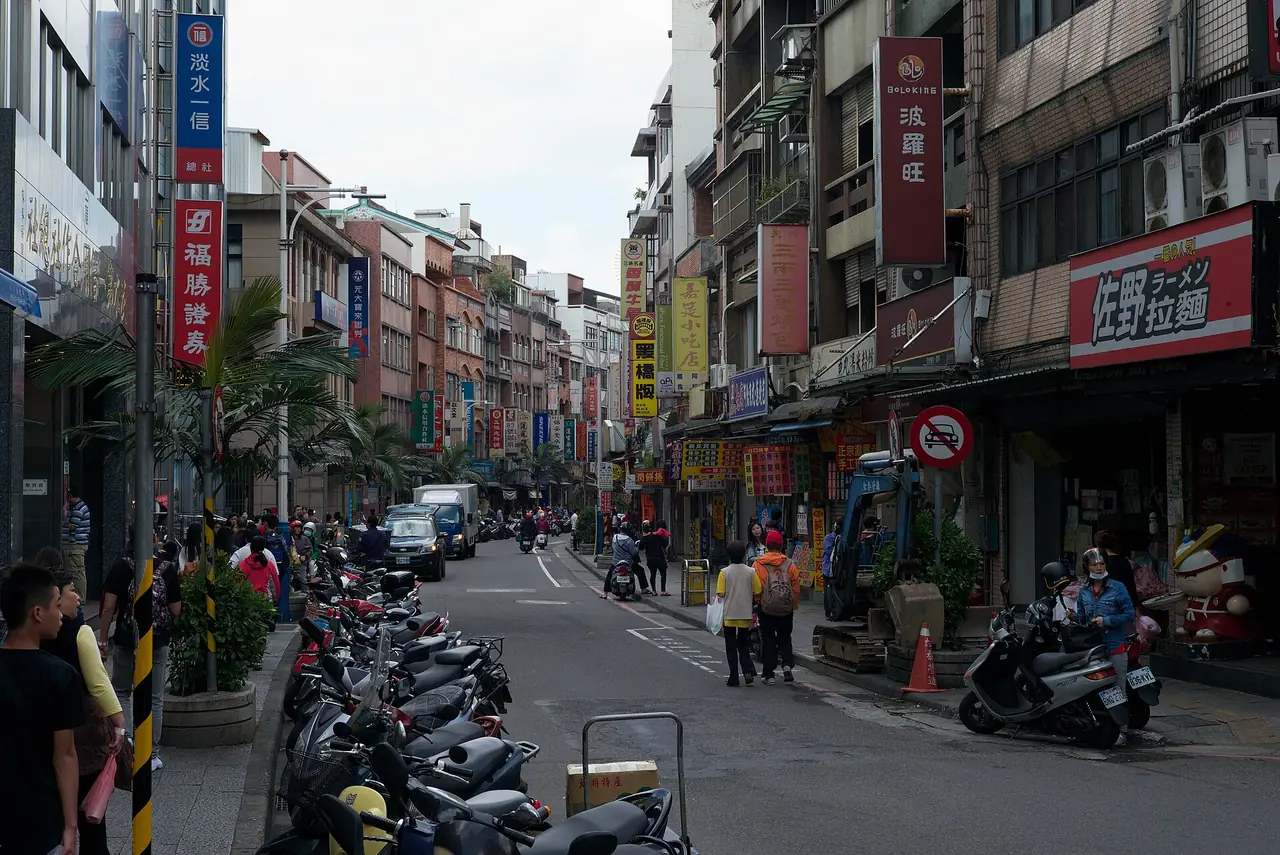 ถนนในตัวเมืองตั้นสุ่ยมีร้านค้าและรถสกู๊ตเตอร์จอดเรียง ภาพปี 2557 จาก Wikimedia Commons ผู้ถ่าย Morgan Calliope สัญญา CC BY 2.0