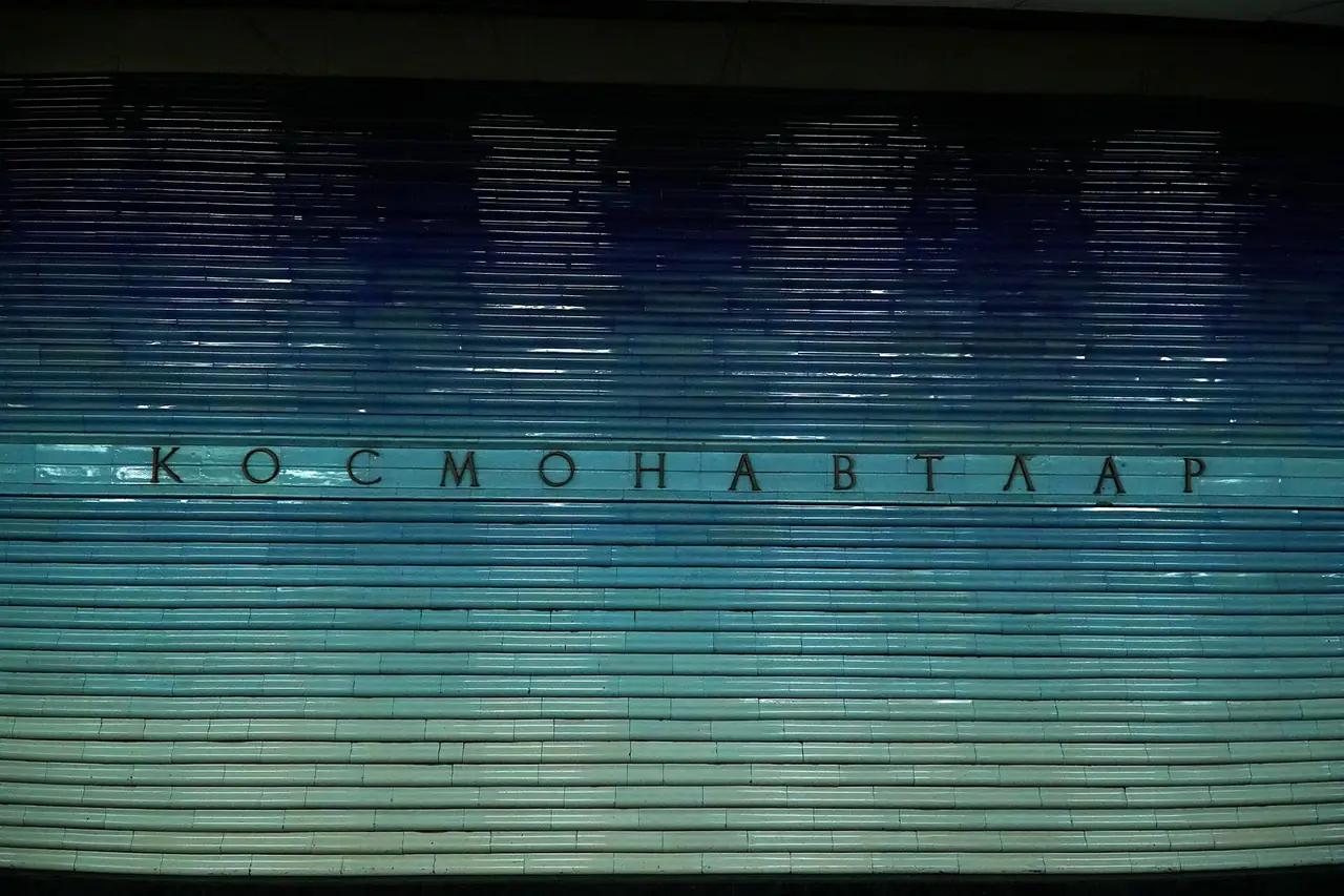 ผนังกระเบื้องไล่สีฟ้าและชื่อสถานี Kosmonavtlar ในรถไฟใต้ดินทาชเคนต์ ภาพจาก Wikimedia Commons ผู้ถ่าย Adam Harangozó สัญญา CC BY-SA 4.0 ภาพนี้เห็นเฉพาะผนังชื่อสถานี ไม่ใช่ทั้งชานชาลา