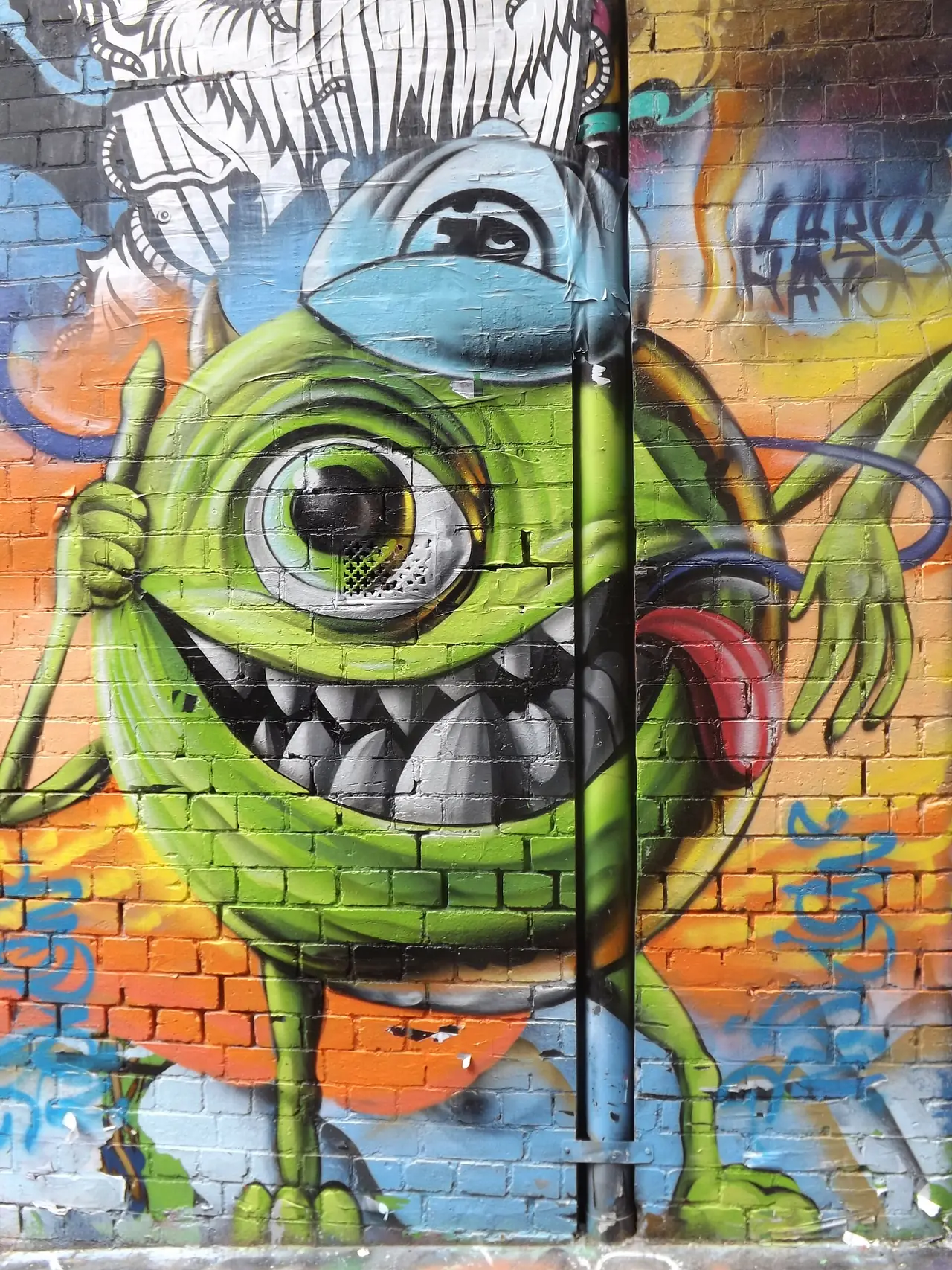งานกราฟฟิตี้ตัวการ์ตูนสีเขียวบนผนังอิฐใน Hosier Lane เมลเบิร์น งานศิลปะเปลี่ยนไปเรื่อย ๆ ภาพจาก Wikimedia Commons ผู้ถ่าย SuperJew สัญญา CC BY-SA 4.0