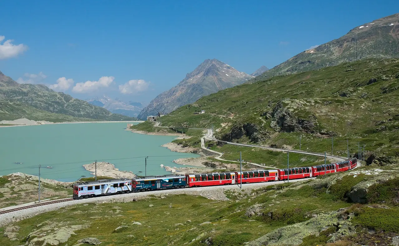 ขบวน Bernina Express เลียบทะเลสาบ Lago Bianco ใกล้ช่องเขา Bernina ภาพจาก Wikimedia Commons ผู้ถ่าย Kabelleger / David Gubler สัญญา CC BY-SA 3.0 ไม่ทราบปีที่ถ่าย ภาพหน้าร้อน
