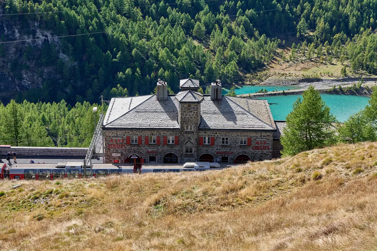 สถานี Alp Grüm บนเส้นทาง Bernina ที่มองเห็นทะเลสาบเขียวมรกตอยู่ด้านหลัง ภาพจาก Wikimedia Commons ผู้ถ่าย Leonhard Lenz สัญญา CC0 ภาพวันที่ 27 ก.ย. 2565 เป็นภาพประกอบต้นฤดูใบไม้ร่วง