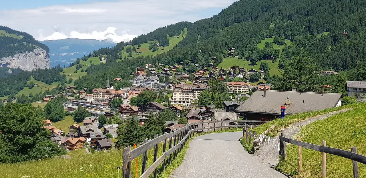 ทางเดินเข้าหมู่บ้านเวนเกน มองเห็นหุบเขา Lauterbrunnen ด้านหลัง ภาพจาก Wikimedia Commons ผู้ถ่าย Armineaghayan สัญญา CC BY-SA 4.0 ภาพช่วงฤดูร้อน ไม่ทราบปีที่ถ่าย