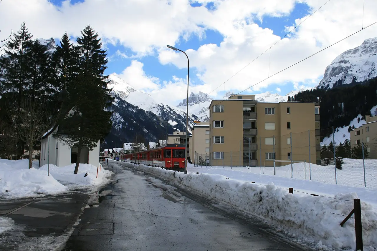 รถไฟสีแดงวิ่งเข้าสู่หมู่บ้านเอนเกลแบร์กในฤดูหนาว ภาพจาก Wikimedia Commons ผู้ถ่าย Badener สัญญา CC BY-SA 3.0 ไม่ทราบปีที่ถ่าย เป็นภาพประกอบ ถนนและอาคารอาจเปลี่ยนไปแล้ว