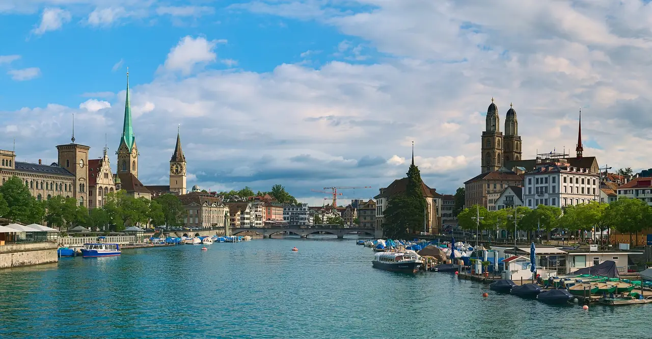 ภาพถ่ายจากสะพาน Quaibrücke มองแม่น้ำ Limmat ยอดโบสถ์ Fraumünster ทางซ้ายและ Grossmünster ทางขวา ภาพจาก Wikimedia Commons ผู้ถ่าย Daniel Kraft สัญญา CC BY-SA 3.0 ภาพวันที่ 2 ก.ค. 2563 ฤดูร้อน เป็นภาพประกอบ