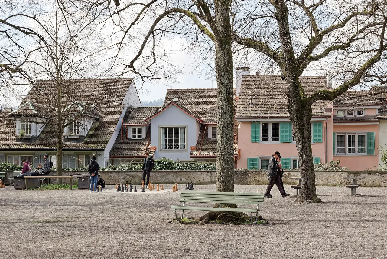 ลาน Lindenhof ในเมืองเก่าซูริกที่มีกระดานหมากรุกยักษ์และบ้านหลังคากระเบื้อง ภาพจาก Wikimedia Commons ผู้ถ่าย Jakub Hałun สัญญา CC BY 4.0 ภาพวันที่ 30 มี.ค. 2568 ต้นไม้ยังไม่ผลิใบ