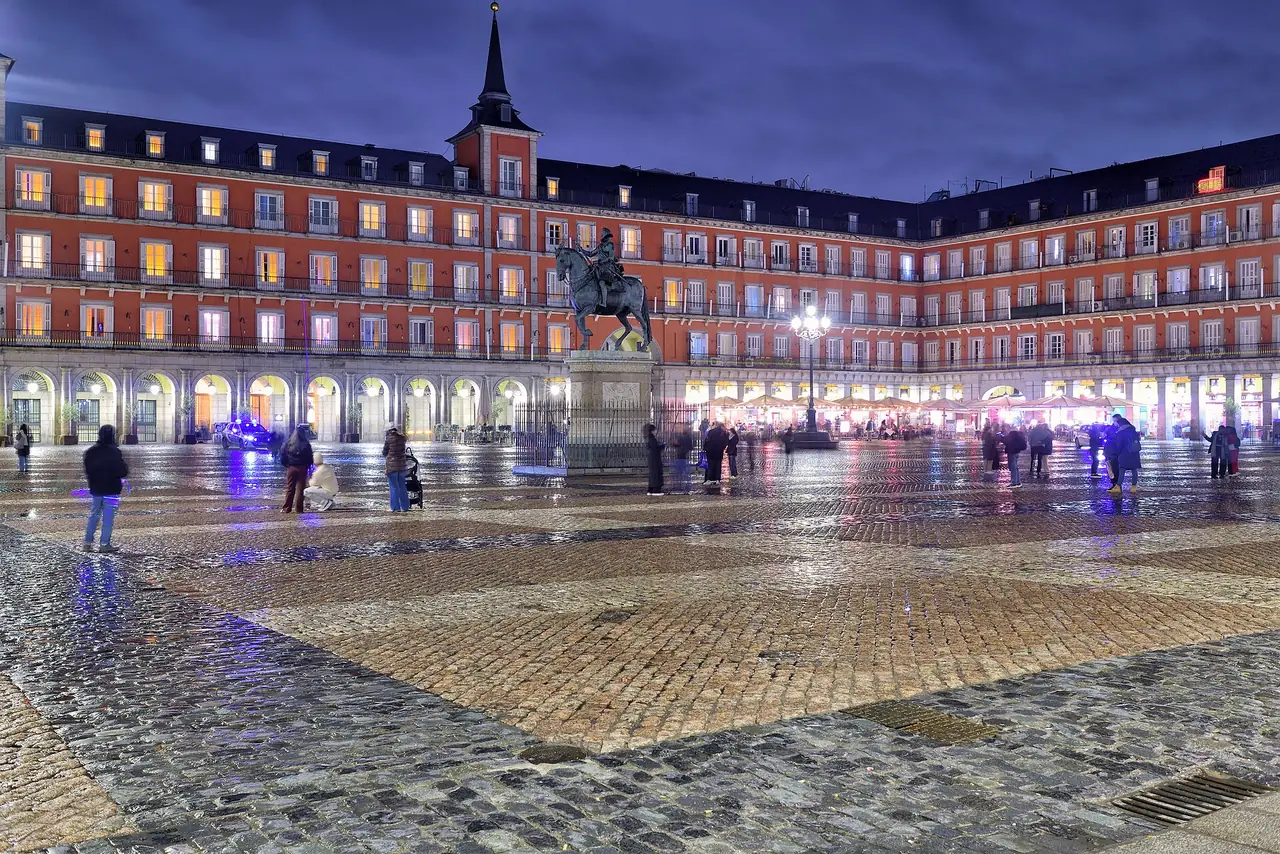 จัตุรัส Plaza Mayor ในมาดริด ยามค่ำที่พื้นเปียก ภาพถ่ายจาก Wikimedia Commons ผู้ถ่าย Javier Perez Montes สัญญา CC BY-SA 4.0 ภาพเดือน ม.ค. 2569
